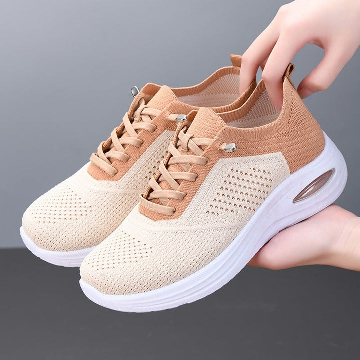 tan and beige knit sneaker with lace-up front and air cushion sole, held by hand