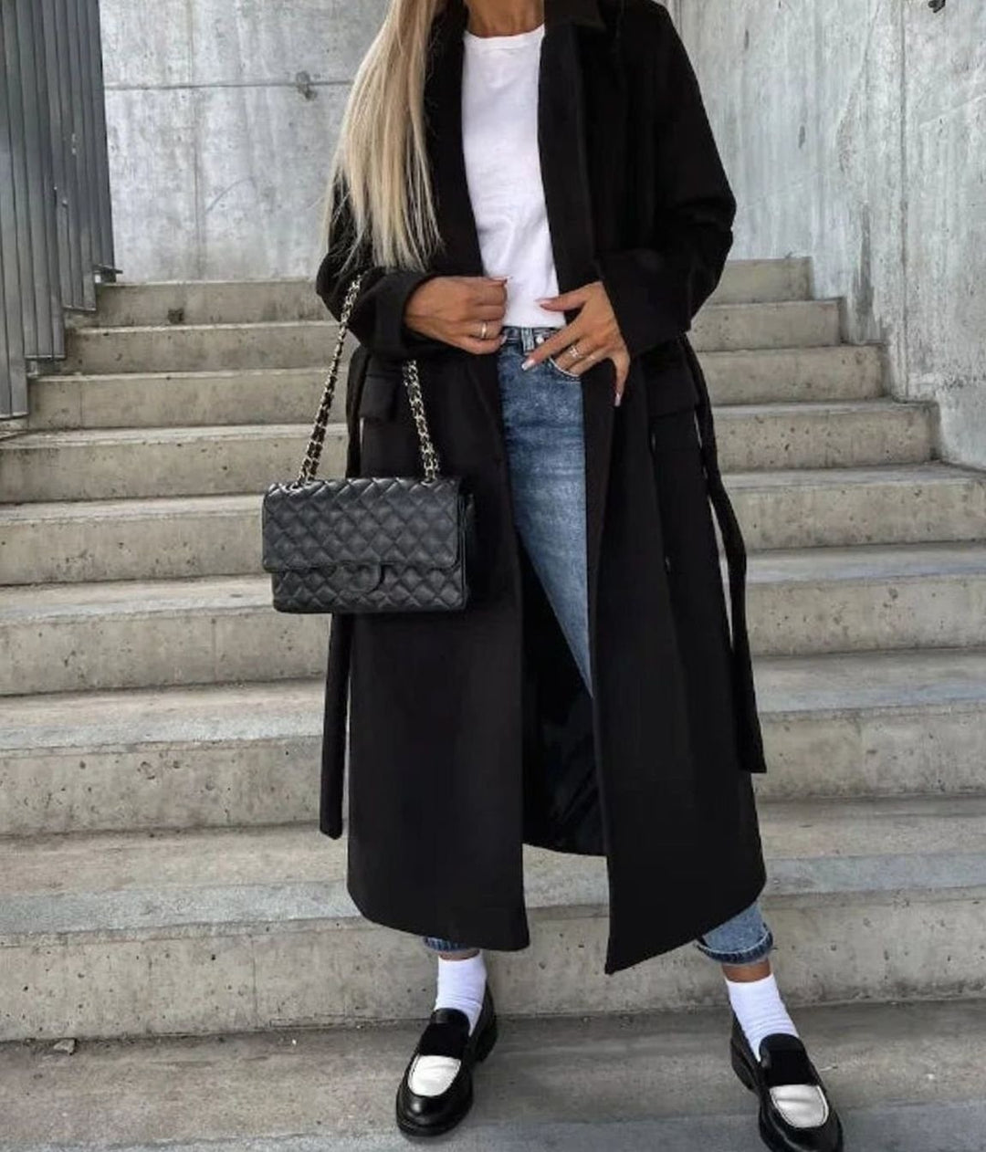 Black double-breasted longline coat worn open over white tee and jeans