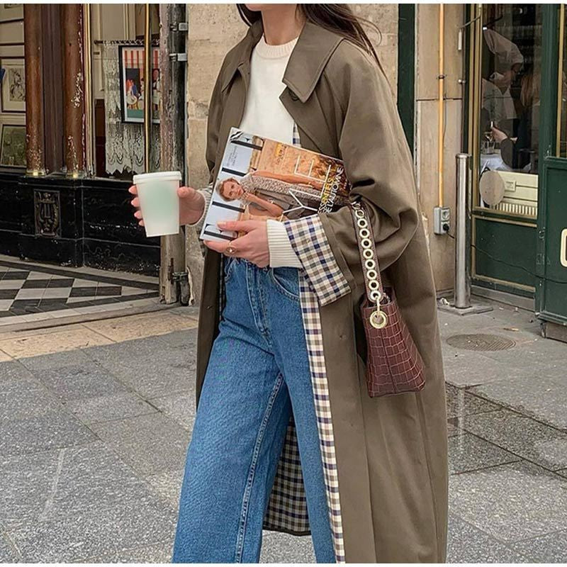 Long khaki trench coat with plaid contrast lining and wide-leg jeans street style