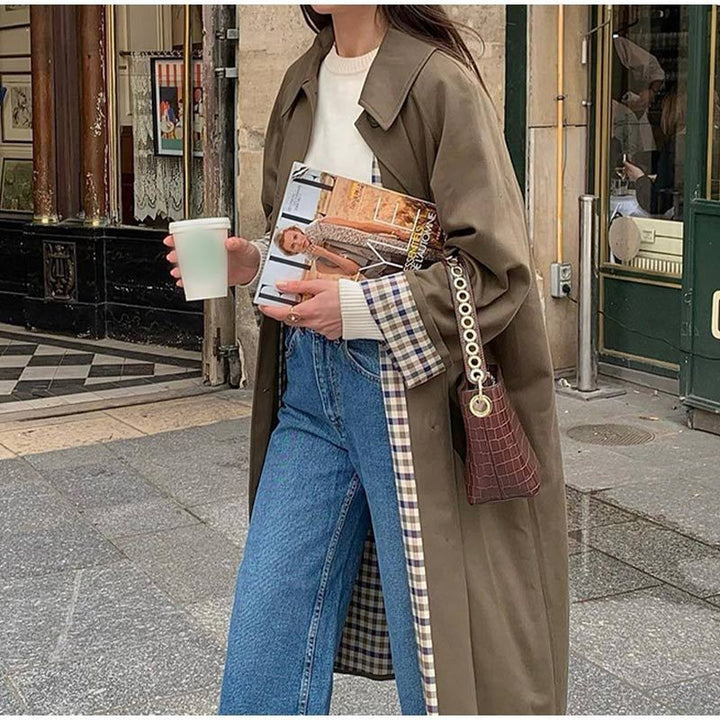 Long khaki trench coat with plaid contrast lining and wide-leg jeans street style