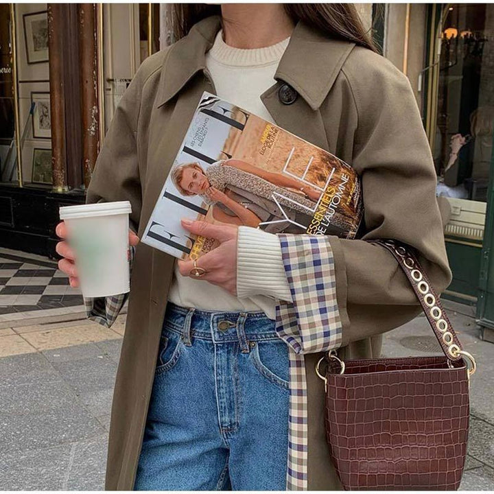 Khaki trench coat detail showing plaid cuff lining and croc-embossed shoulder bag