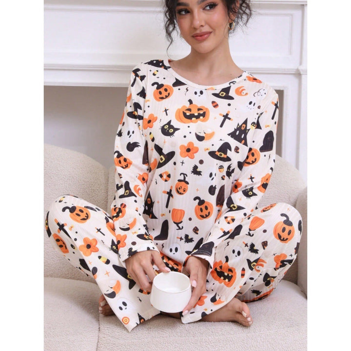 woman in long-sleeve pajama set featuring pumpkins and witch hats, holding mug