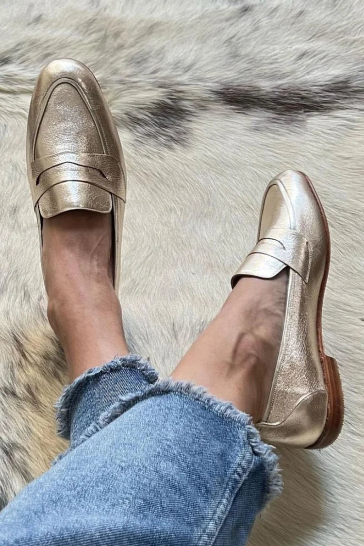 Gold metallic leather penny loafers worn with cropped raw-hem jeans