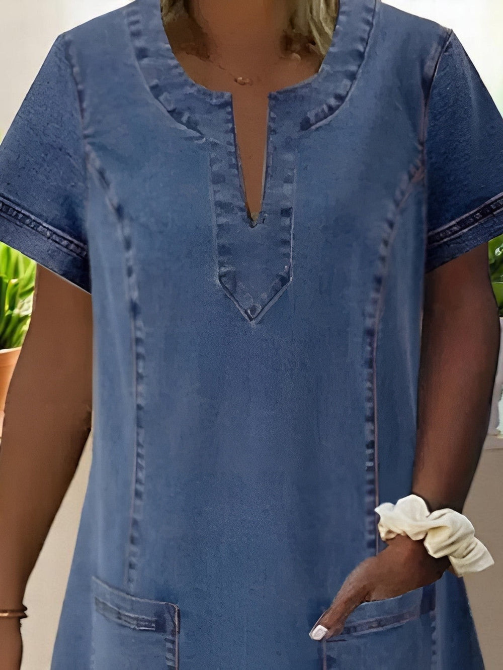 Close-up of denim dress notched V-neckline with contrast topstitching detail