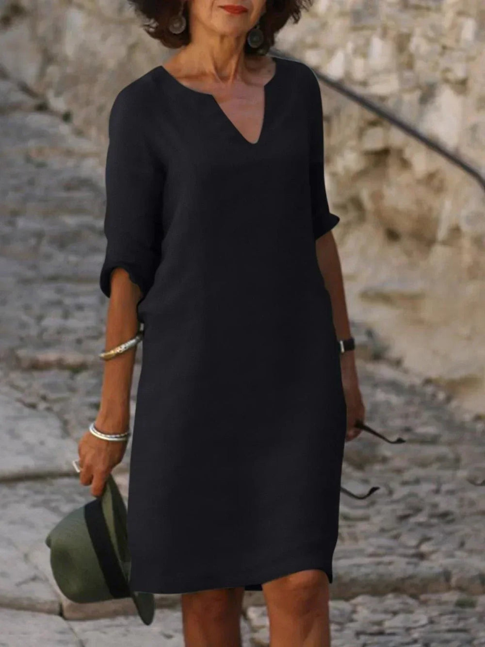 Black notch V-neck shift dress paired with a green hat accessory