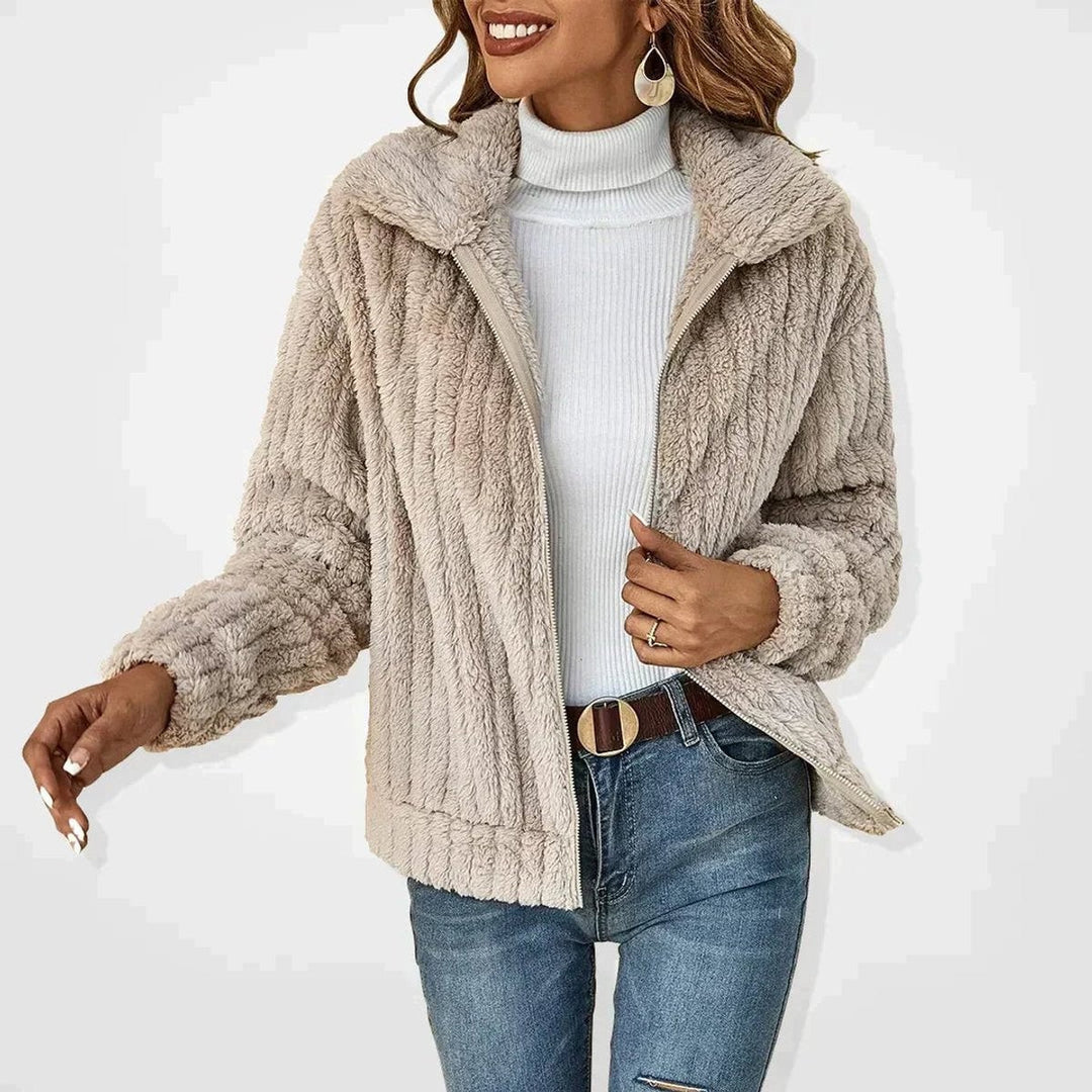 Beige ribbed faux fur zip-up jacket worn over a white polo neck jumper