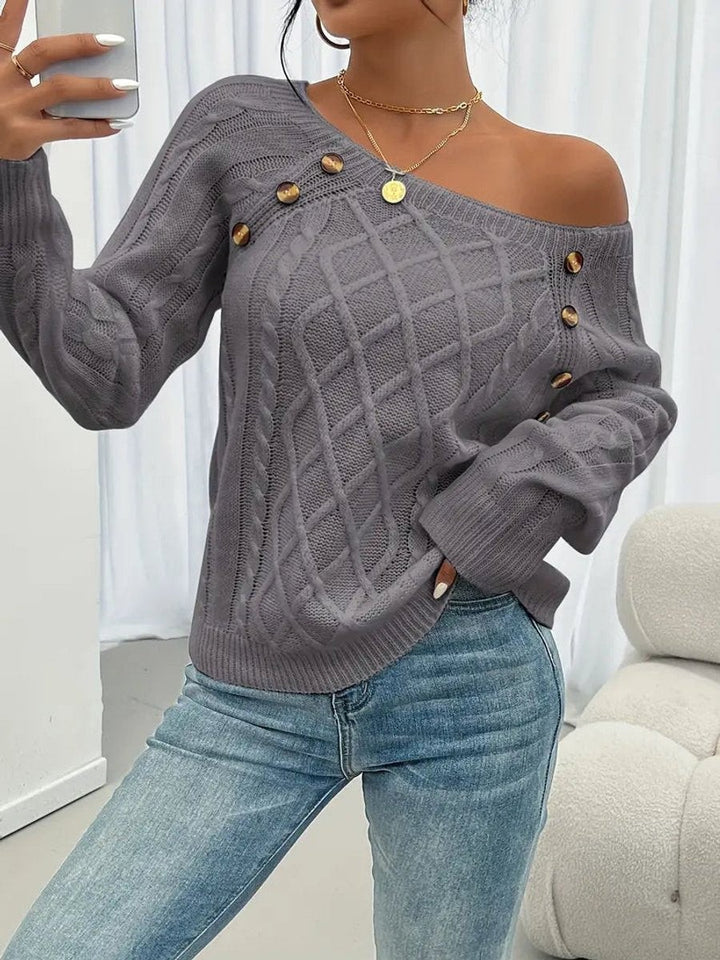 Grey cable knit jumper worn off-shoulder with decorative button trim