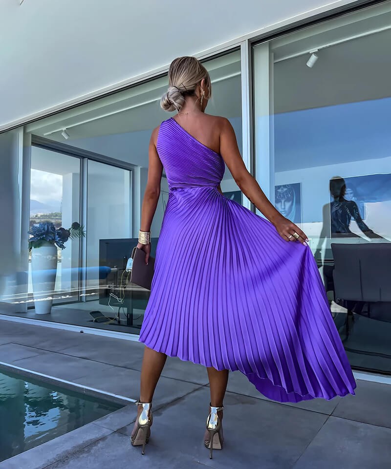 Back view of purple pleated one-shoulder midi dress showing flowing asymmetric hemline