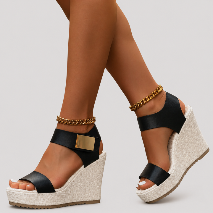 Black ankle strap wedges showing woven wedge heel and gold buckle detail