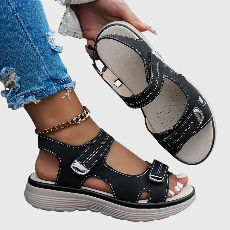 Black platform sandals displayed with hand showing outsole tread pattern