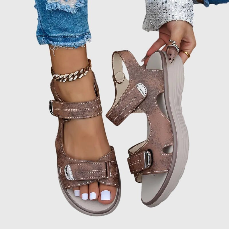 Brown platform sandals held by hand showing sole and strap detail
