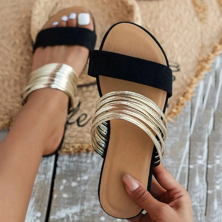 Black slide sandal with multi-strand gold metallic band across toes