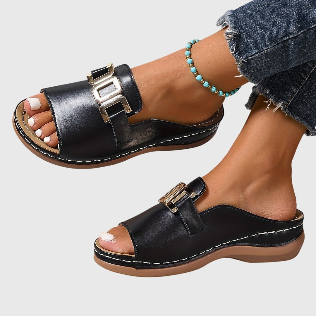 Black slip-on sandals with gold hardware and contrast stitching detail