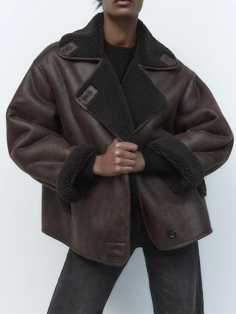 Model wearing oversized brown leather jacket with fleece collar and cuffs, front view