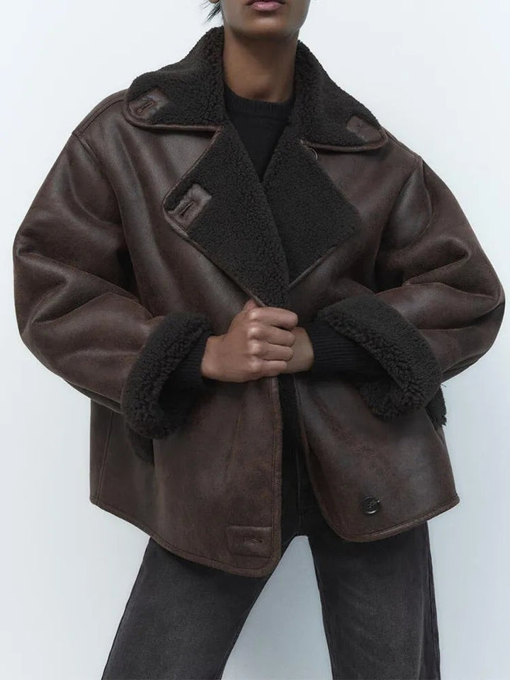 Model wearing oversized brown leather jacket with fleece collar and cuffs, front view