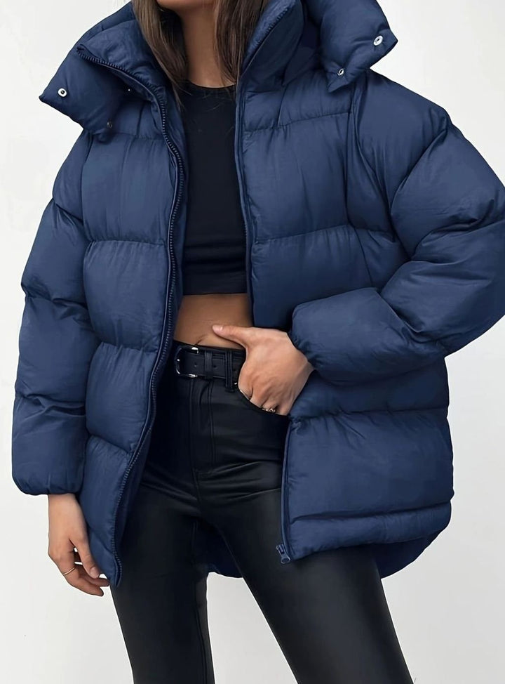 Navy blue zip-up puffer jacket with stand collar, styled with black trousers