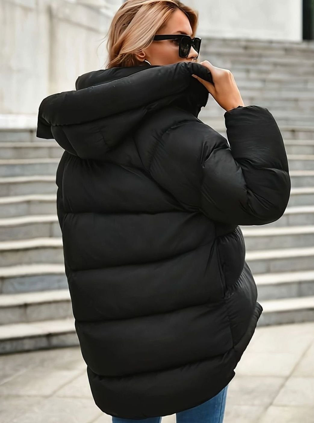 Black hooded puffer jacket shown from behind with quilted panelling detail