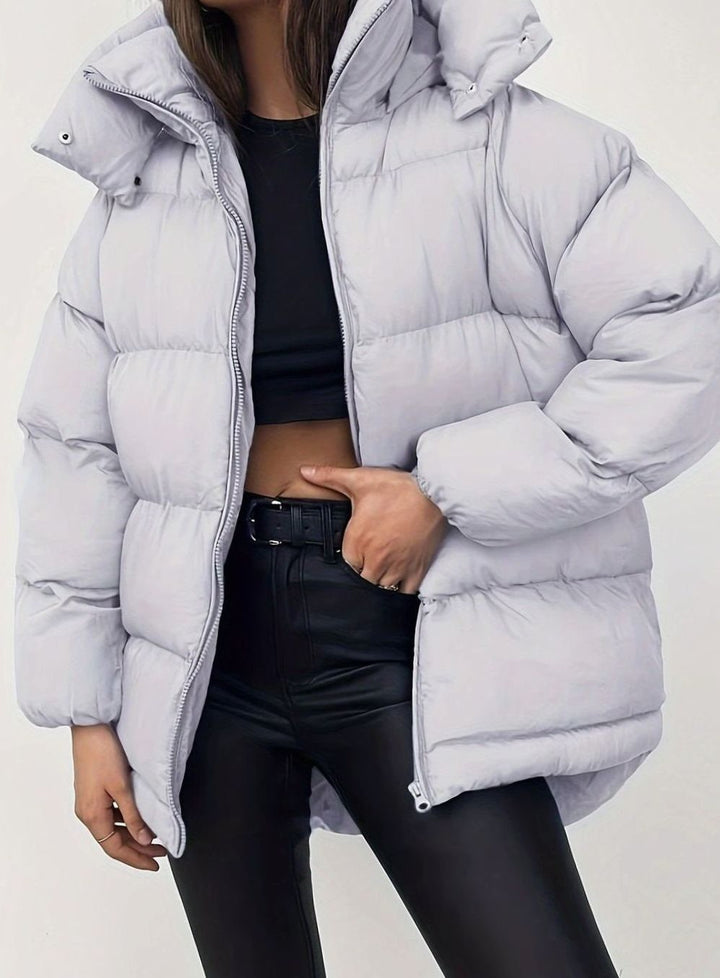 Pale grey quilted puffer jacket with stand collar worn over black crop top