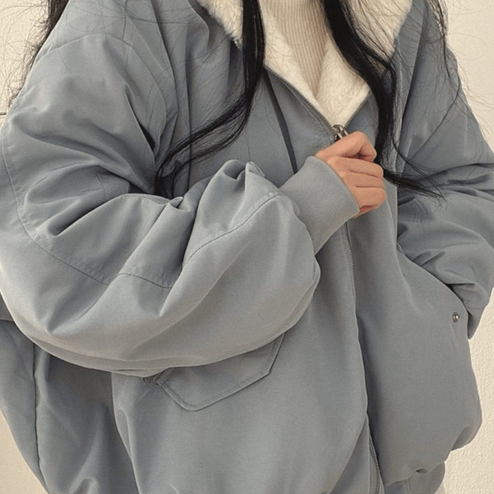 Close-up of dusty blue zip-up jacket showing quilted sleeve and pocket