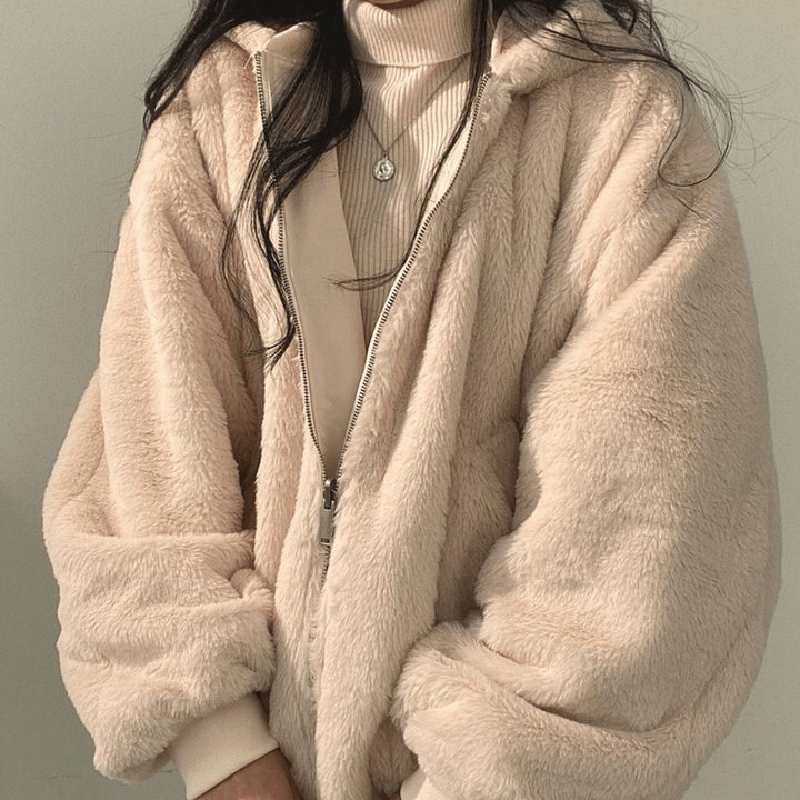 Close-up of fluffy pink teddy jacket with contrast zip fastening