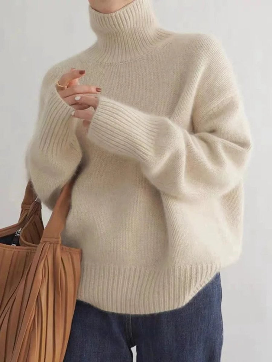 Cream oversized turtleneck sweater with ribbed cuffs paired with a leather tote
