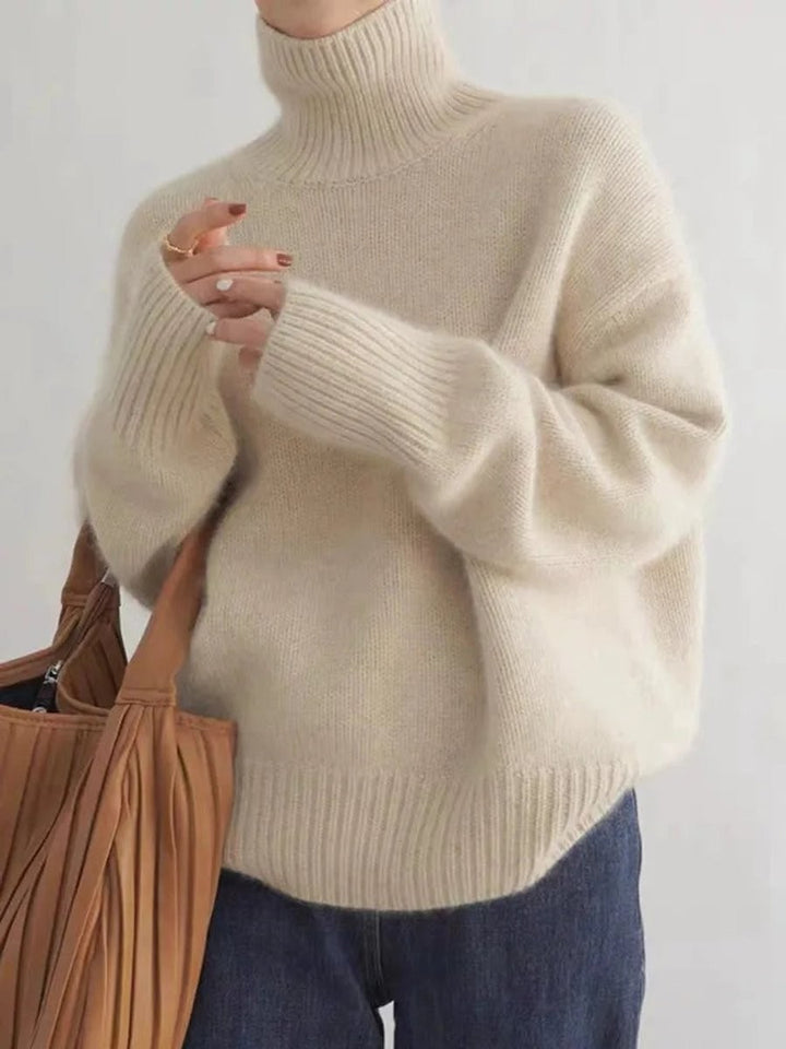 Cream oversized turtleneck sweater with ribbed cuffs paired with a leather tote