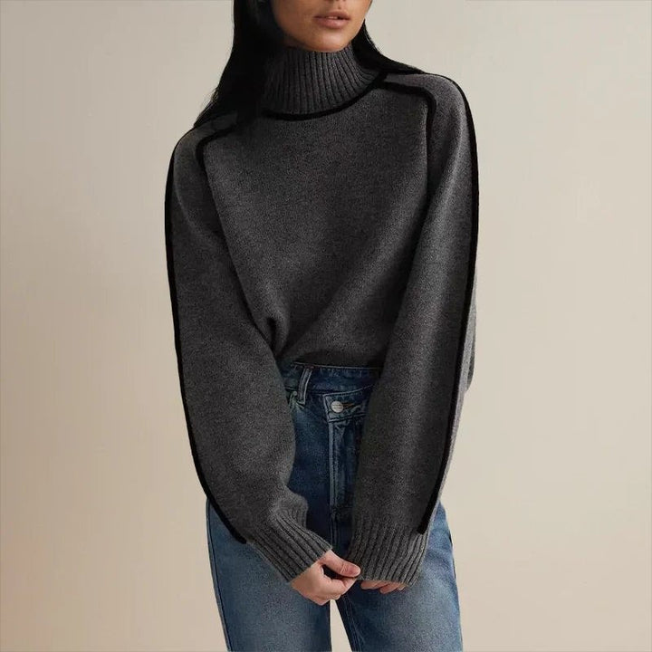 dark gray oversized turtleneck sweater with black piping worn with jeans