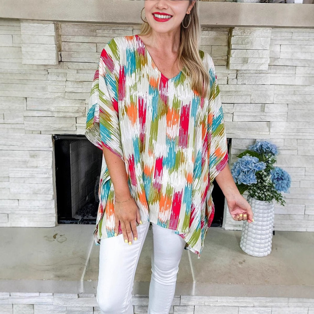 Model wearing loose V-neck tunic top with vibrant brushstroke print
