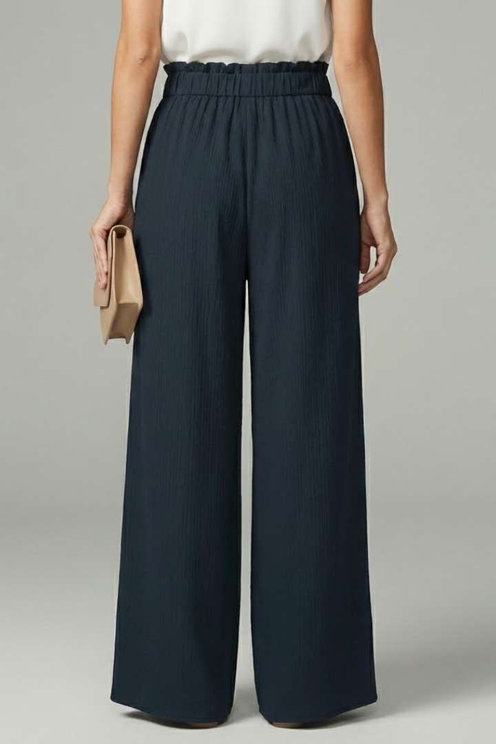 Back view of navy paperbag-waist palazzo trousers showing wide-leg silhouette