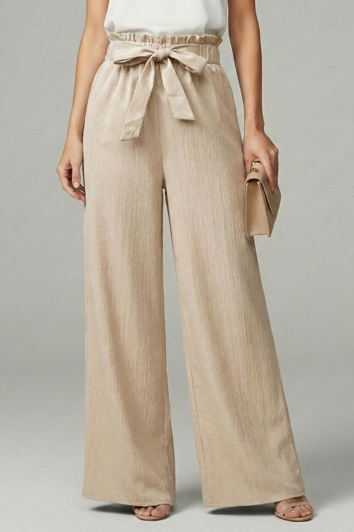 Model wearing beige textured palazzo trousers with paperbag waist and bow tie