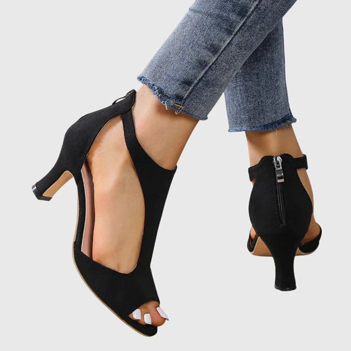Back view of black peep-toe heels with ankle zipper and buckle strap