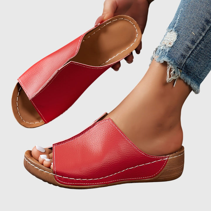 Red wedge slide sandal showing stitched leather upper