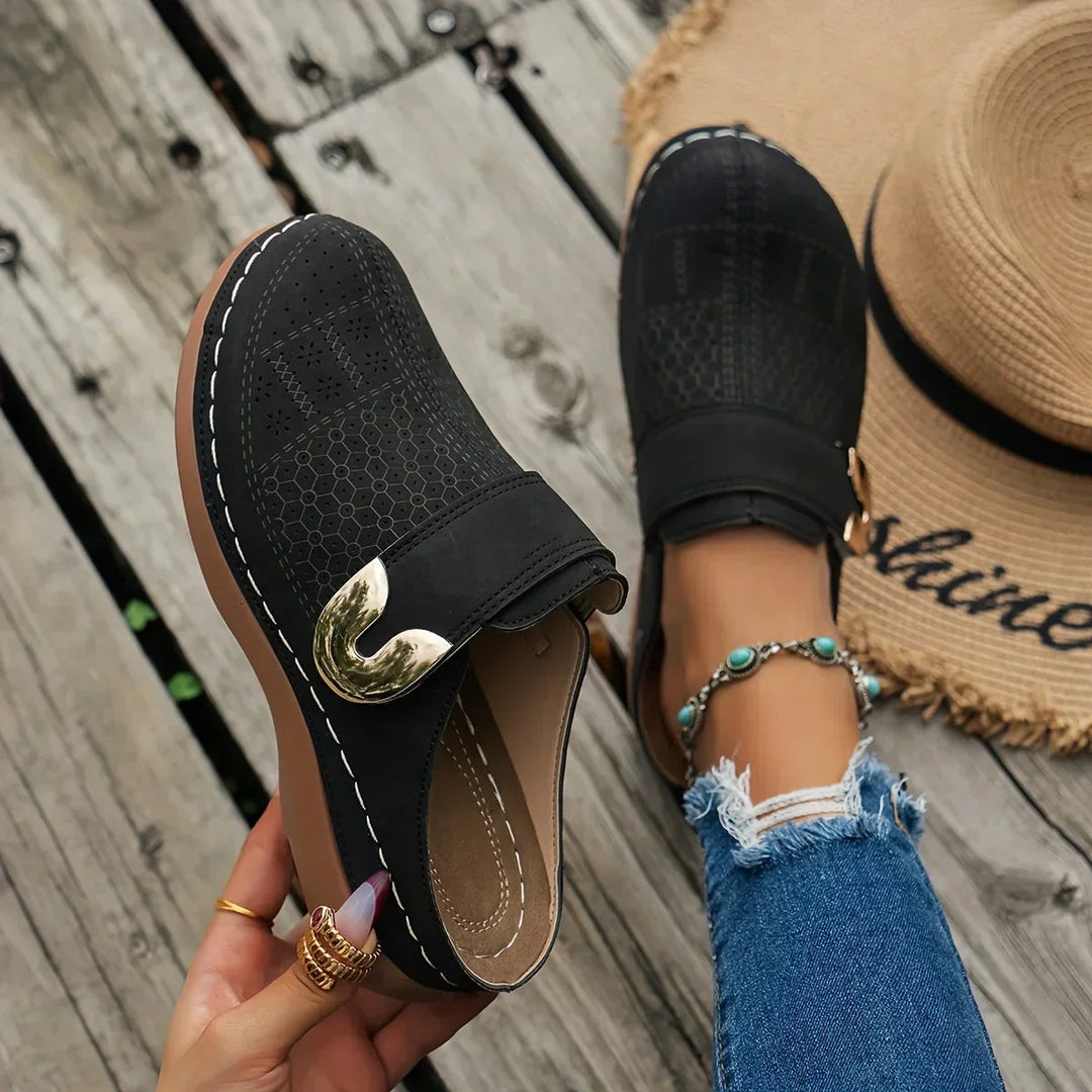 black perforated wedge clog with gold buckle accent and contrast stitching
