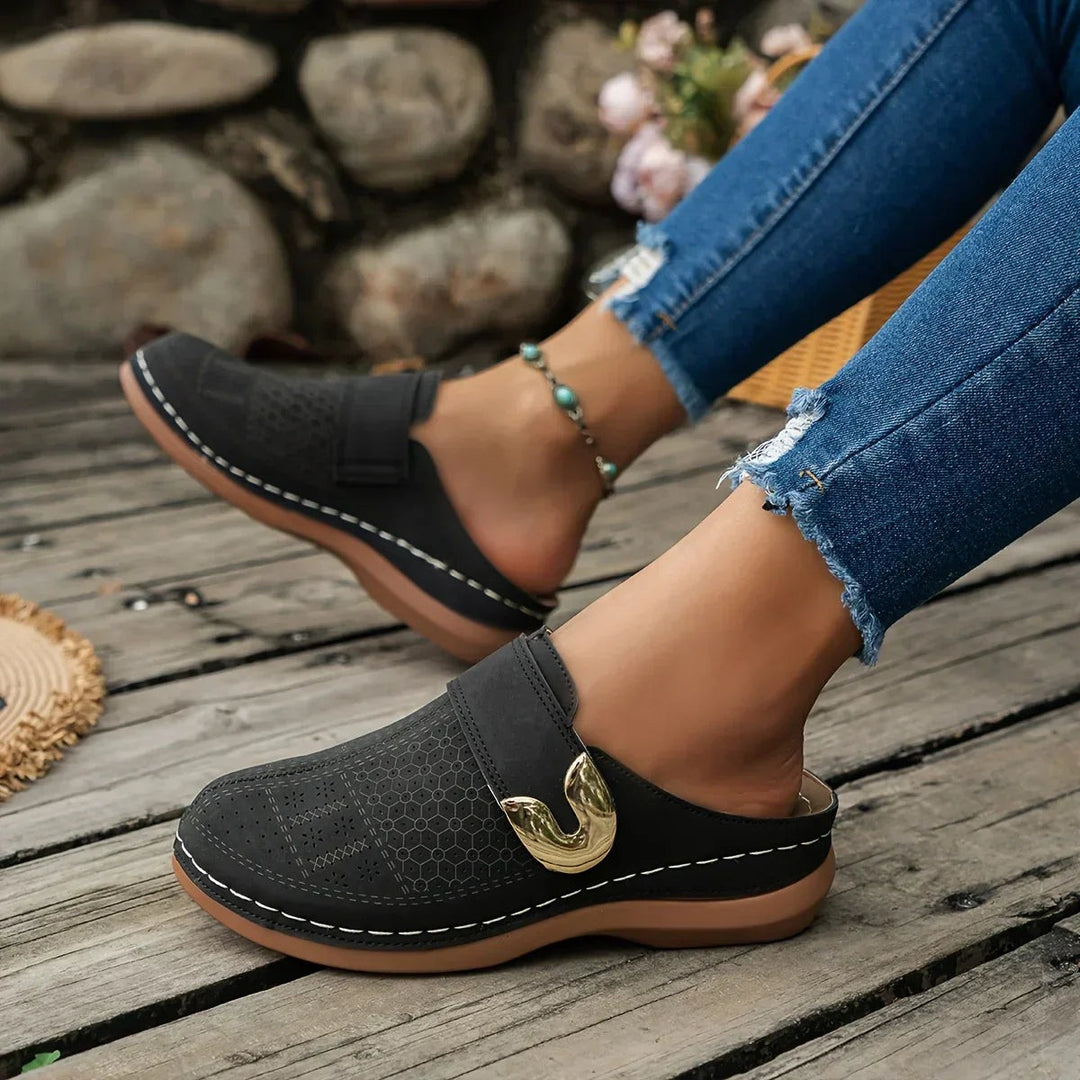 black wedge clog with laser-cut design worn on model's foot