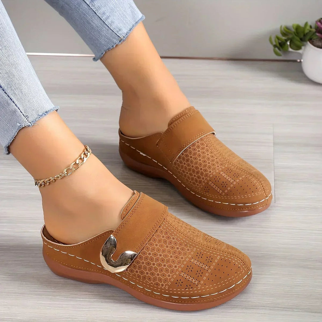 tan perforated wedge clog with gold buckle worn by model