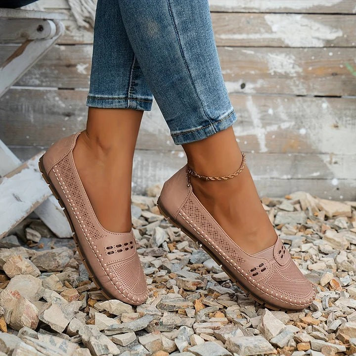 pink perforated leather flats worn with cuffed denim on gravel path