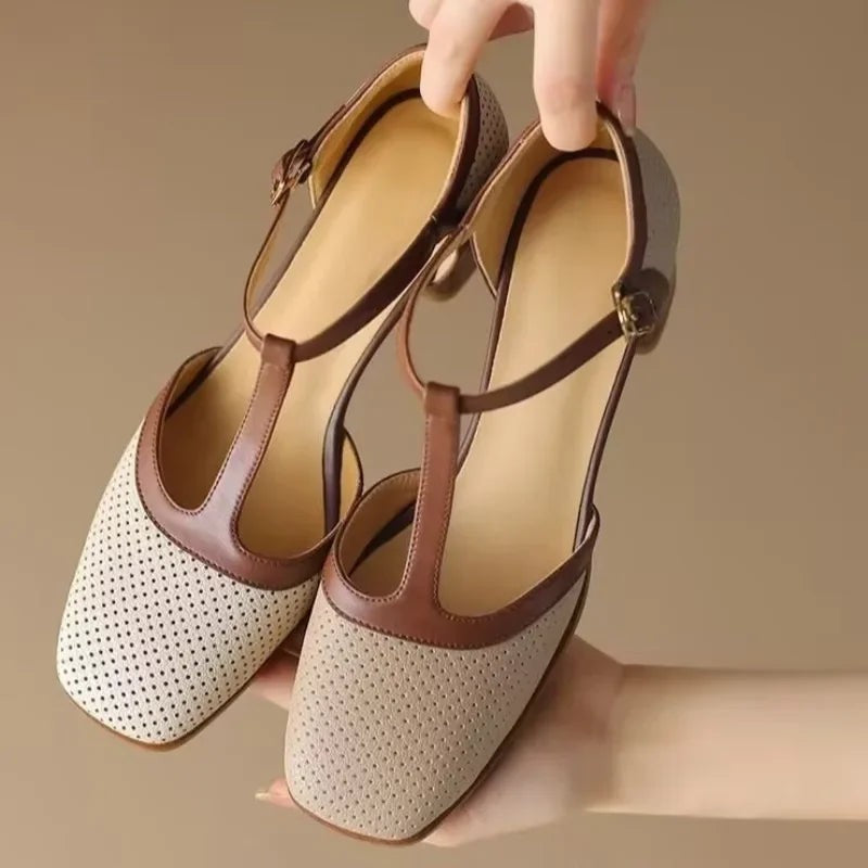 hand holding beige and brown T-strap mid heel pumps with buckle strap