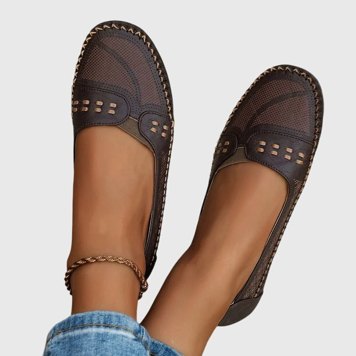 Brown leather loafers with perforated toe, shown mid-step