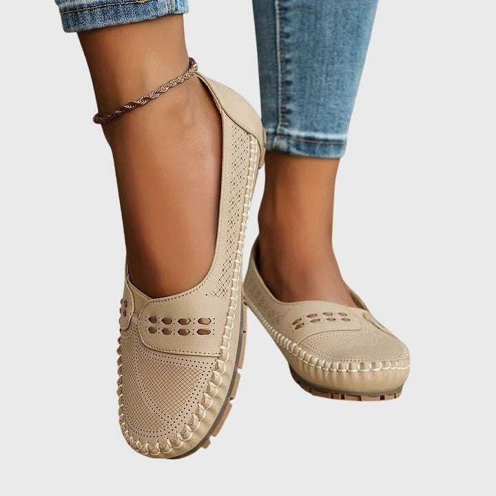 Beige leather orthopedic flats worn on foot with ankle chain