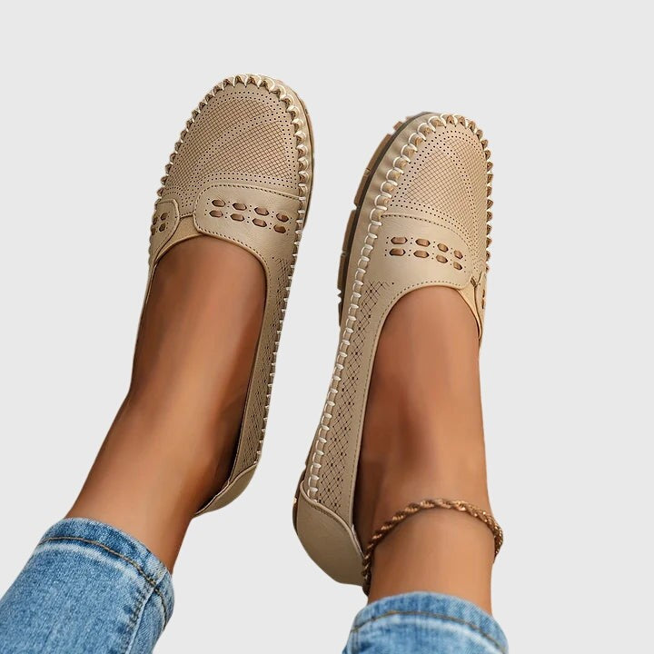 Cream leather loafers with metallic-edge stitching, worn on feet