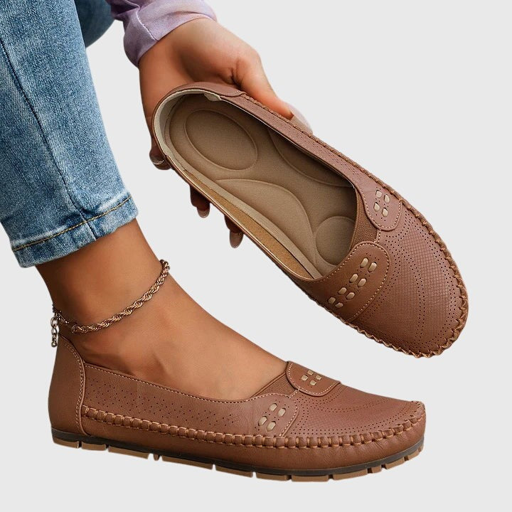 Brown leather orthopedic loafer held open showing cushioned footbed