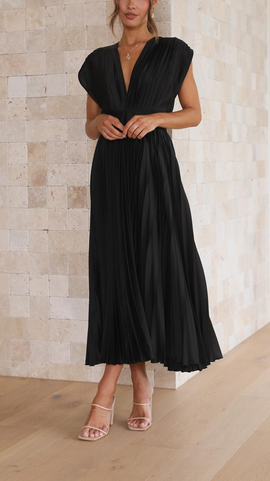 Black pleated satin dress featuring fitted waist and flared skirt