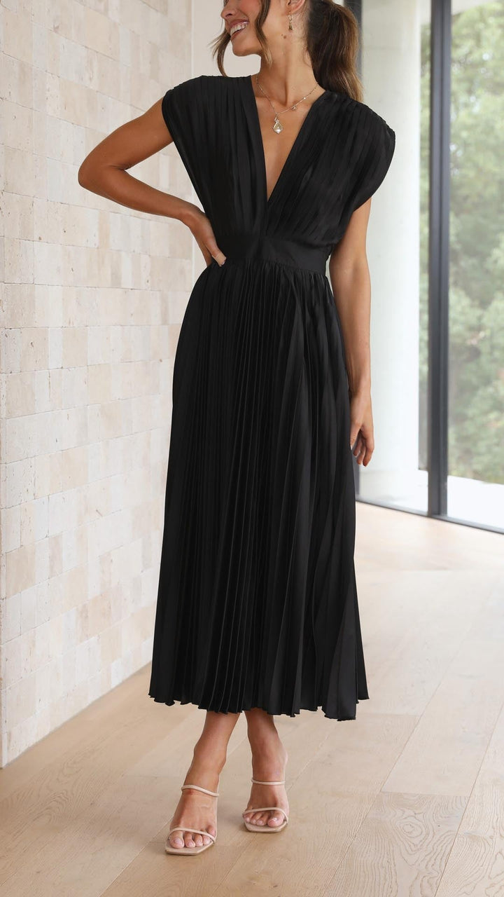 Model walking in black pleated satin midi dress with cinched waist