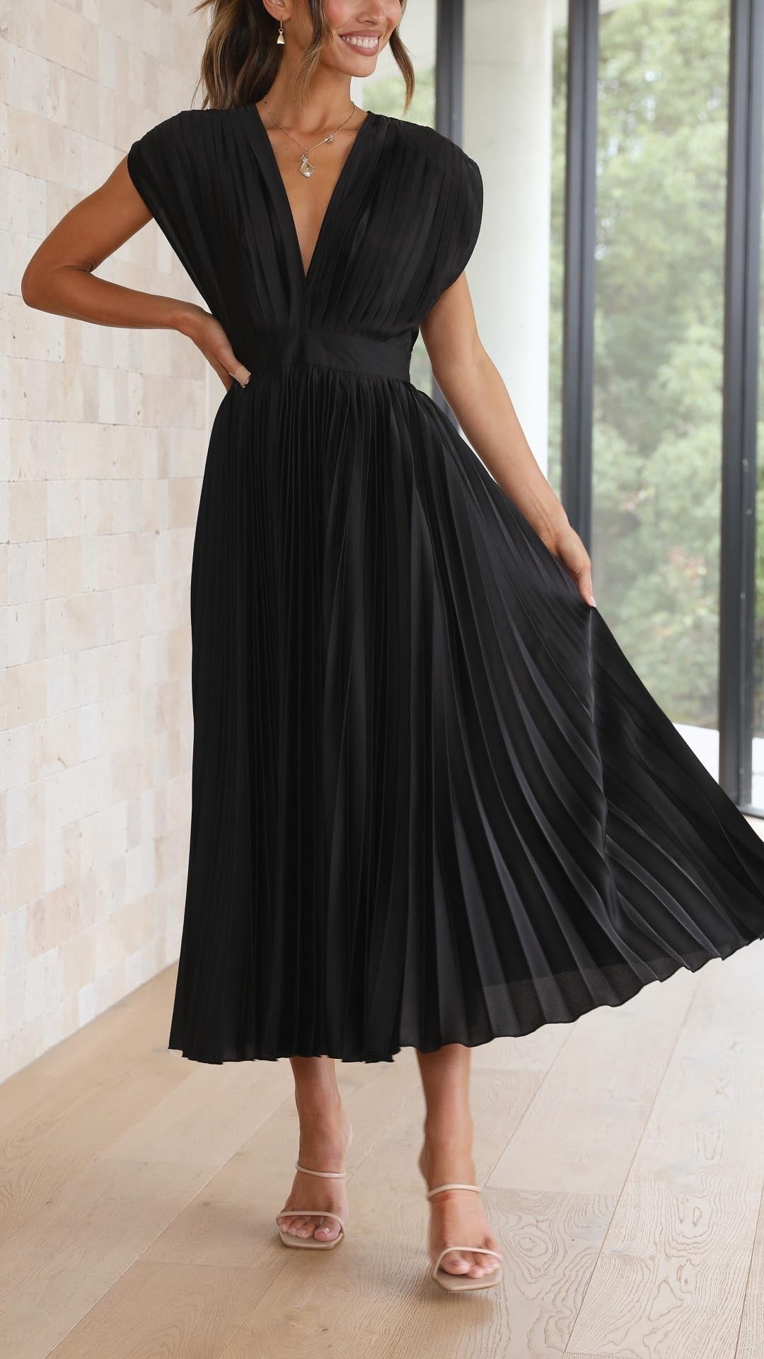 Black pleated satin dress swirling to show flowing pleated skirt