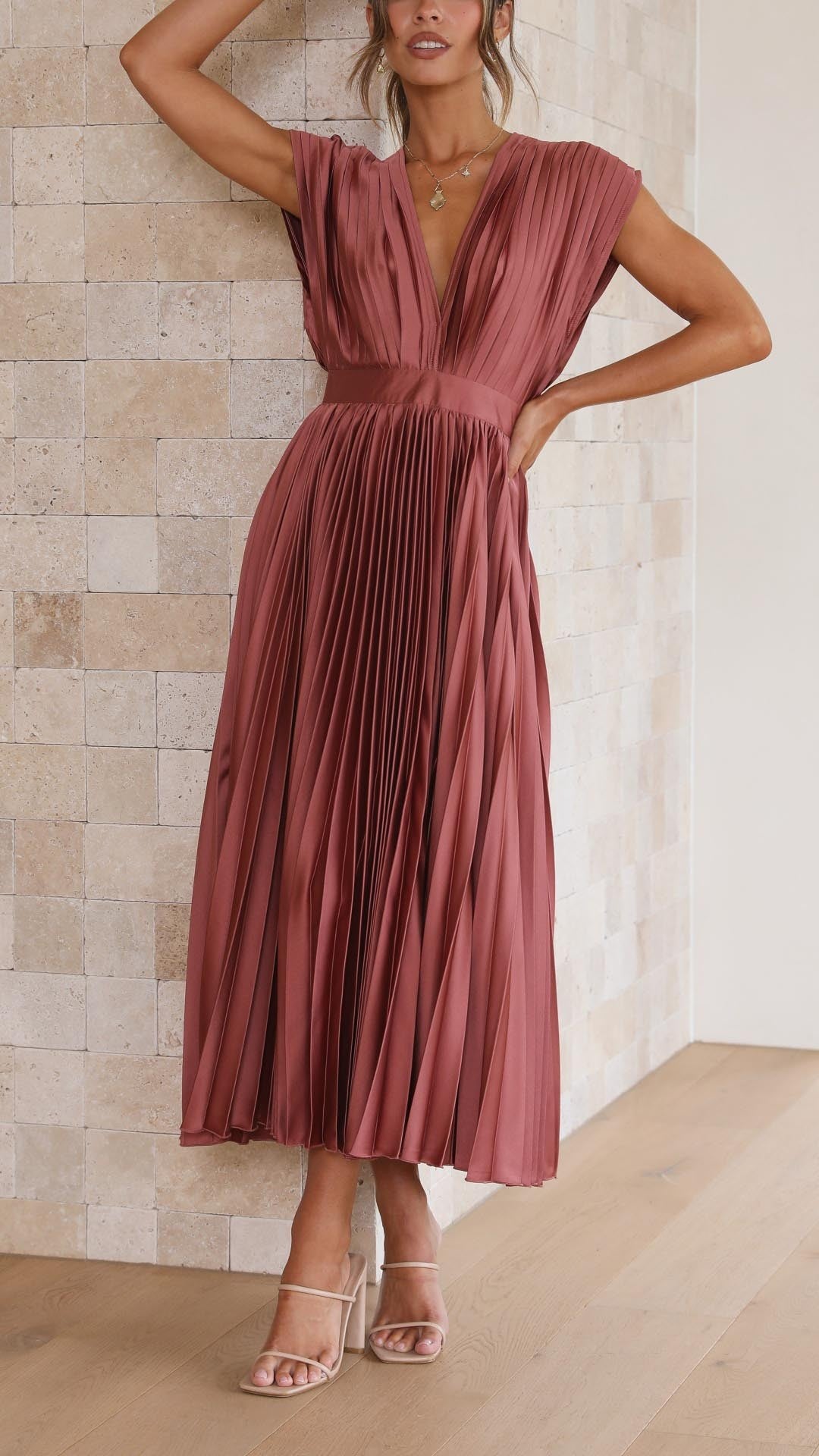 Rust pink pleated satin dress featuring cinched waist and flowy skirt