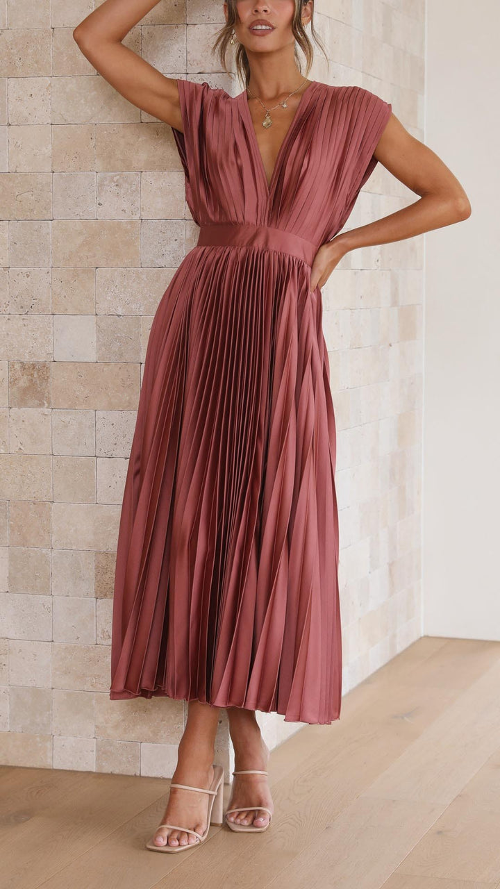 Rust pink pleated satin dress featuring cinched waist and flowy skirt