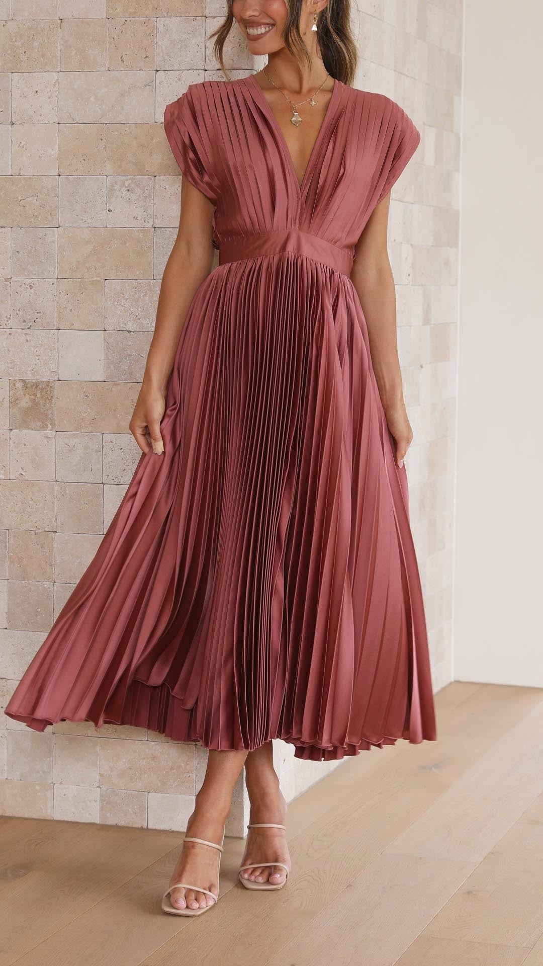 Model twirling in rust pink pleated satin midi dress with V-neckline