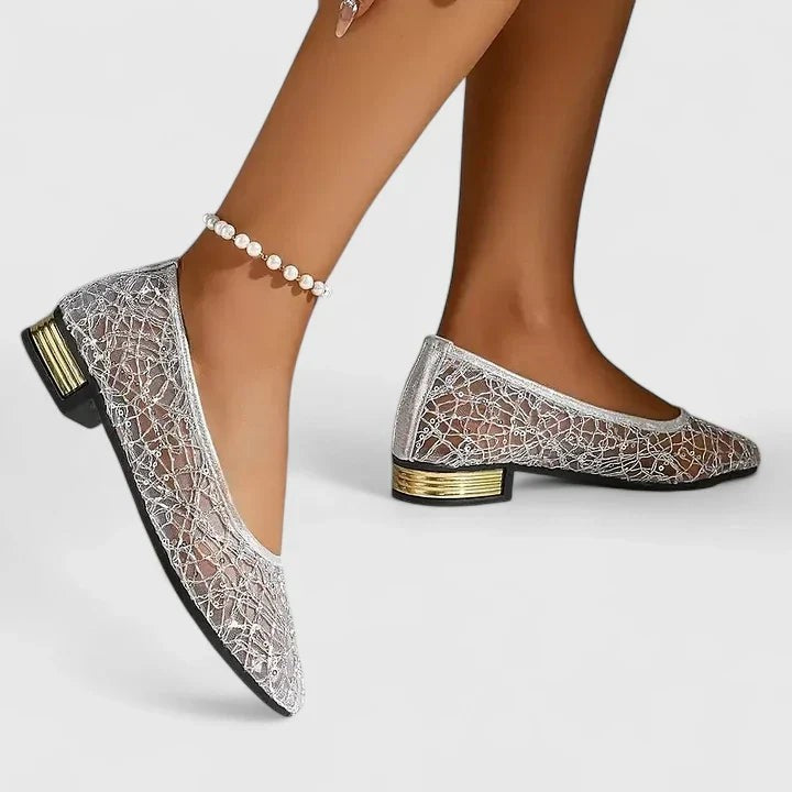 Model stepping in silver lace pointed-toe flats with metallic heel accent