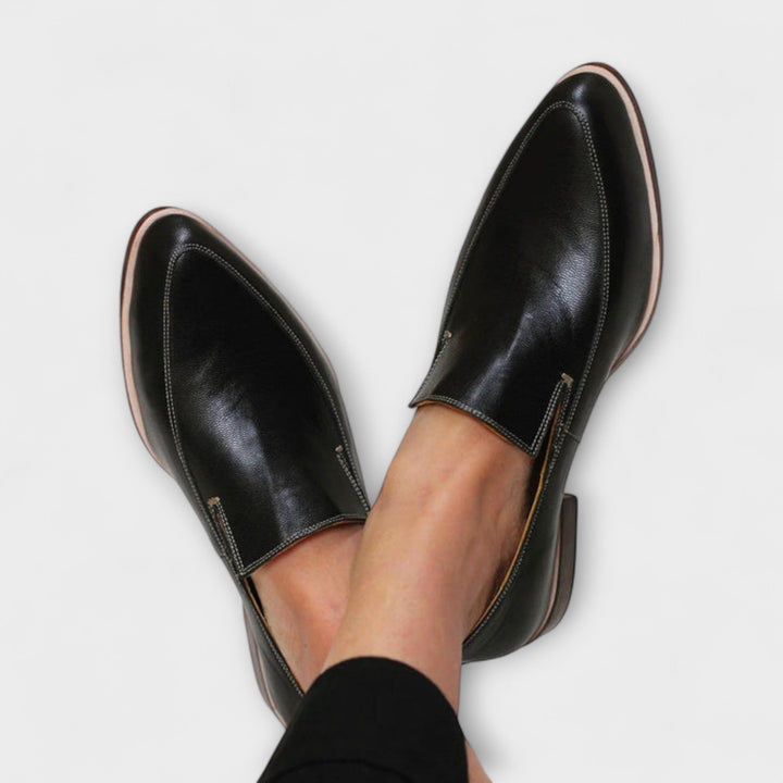 Black leather pointed-toe loafers with contrast stitching and tan sole trim