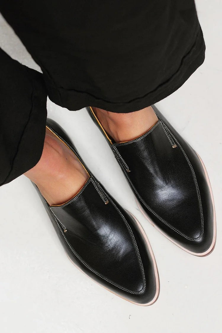 Overhead view of black leather loafers paired with cropped black pants